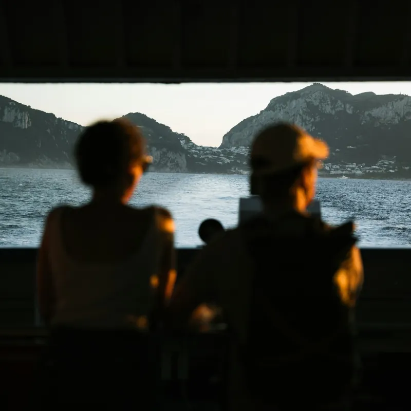 Dos personas en un barco mirando la costa al atardecer